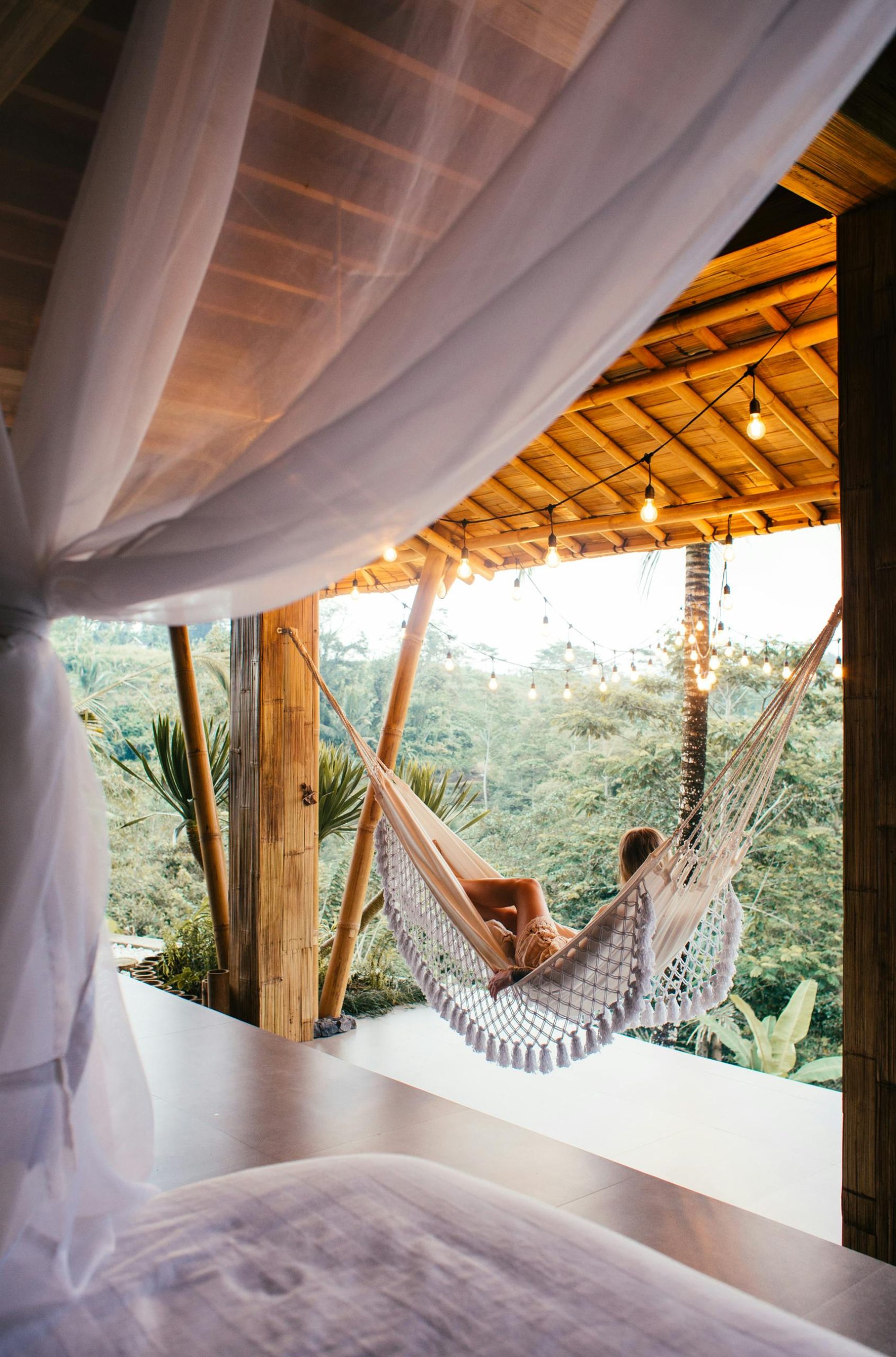 Woman lounging in hammock at tropical resort, enjoying serene view.